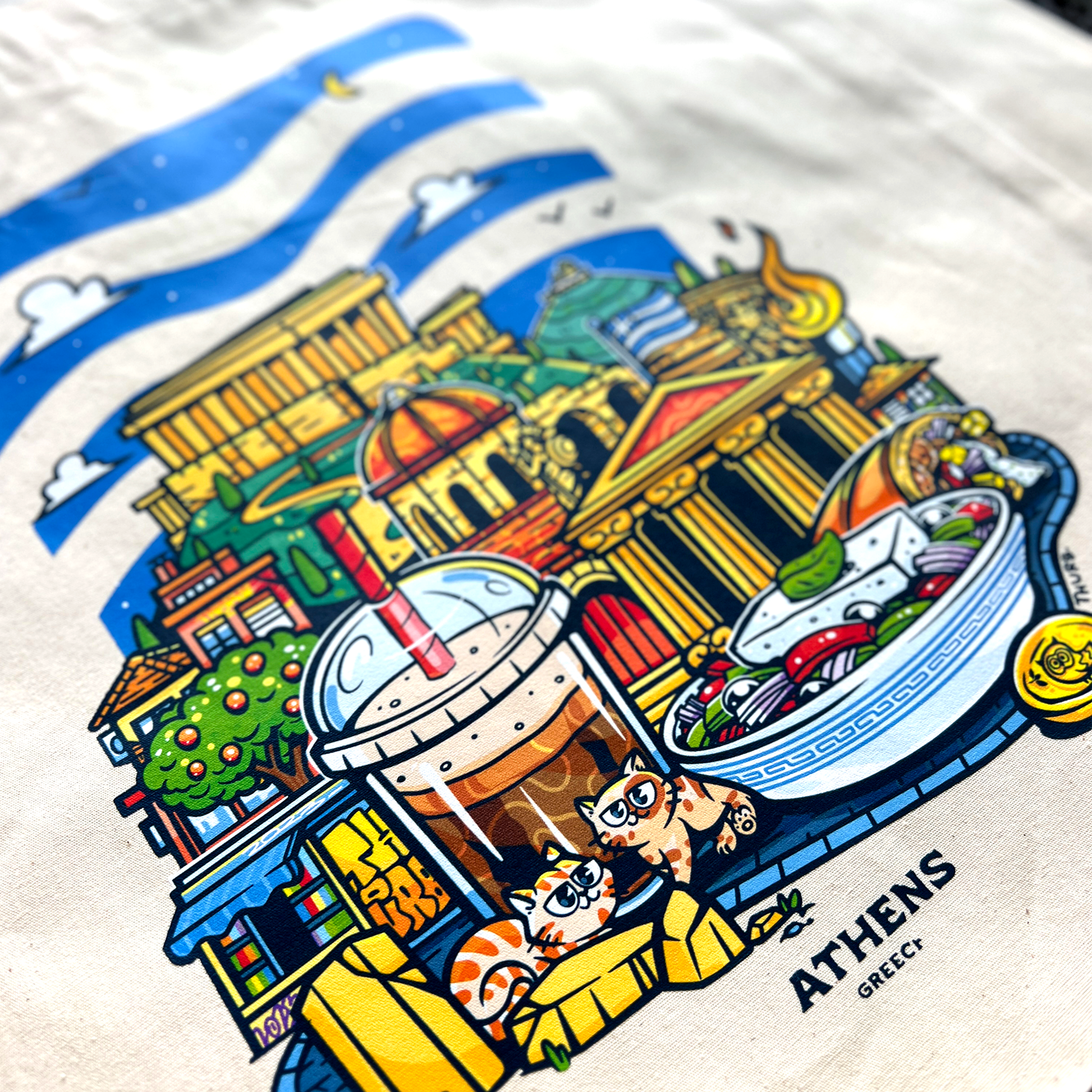 Tote bag avec une image de la ville d'Athènes avec pleins d'éléments représentants la ville comme des boissons, des plats et des monuments.