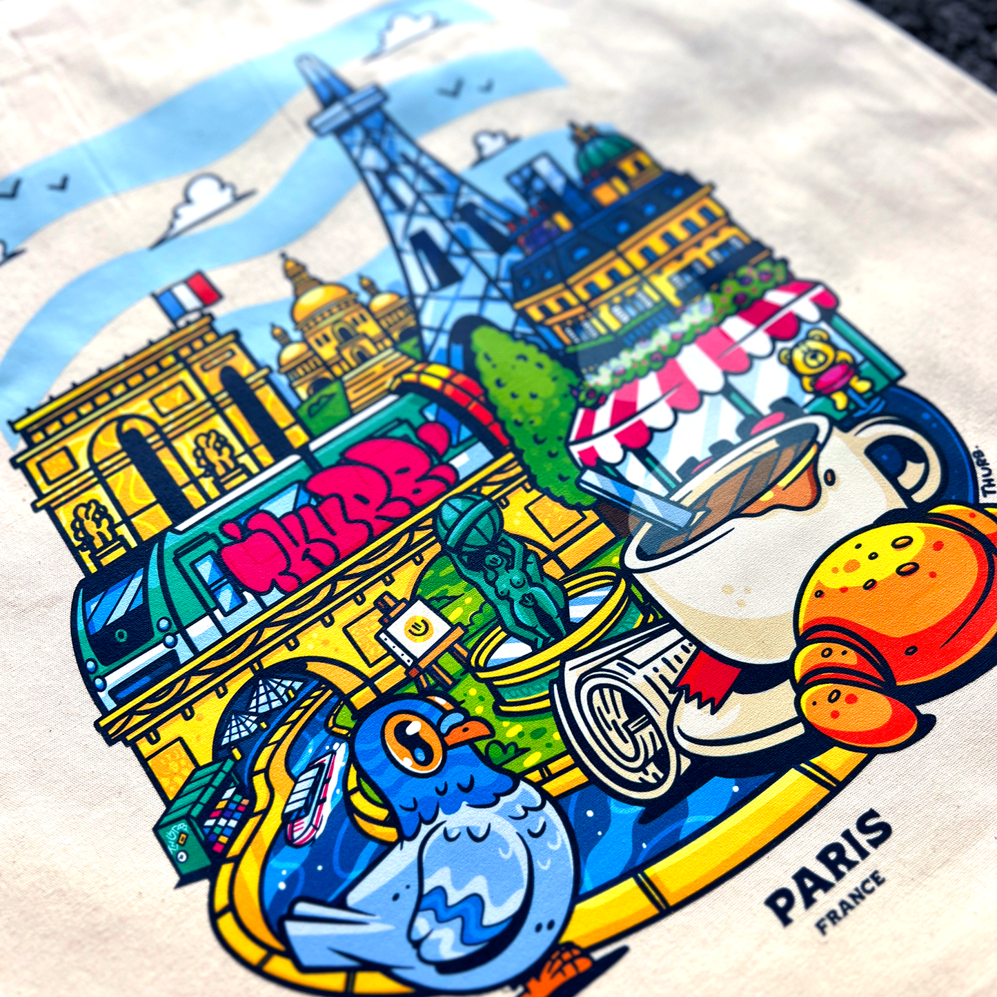 Tote bag avec une image de la ville de Paris avec pleins d'éléments représentants la ville comme des boissons, des plats et des monuments.